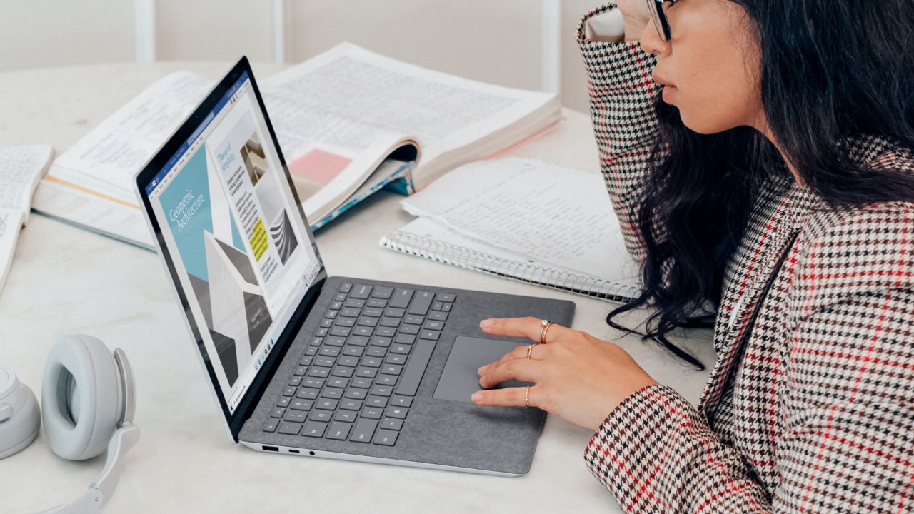 Asian woman with glasses wearing plaid blazer designing on computer