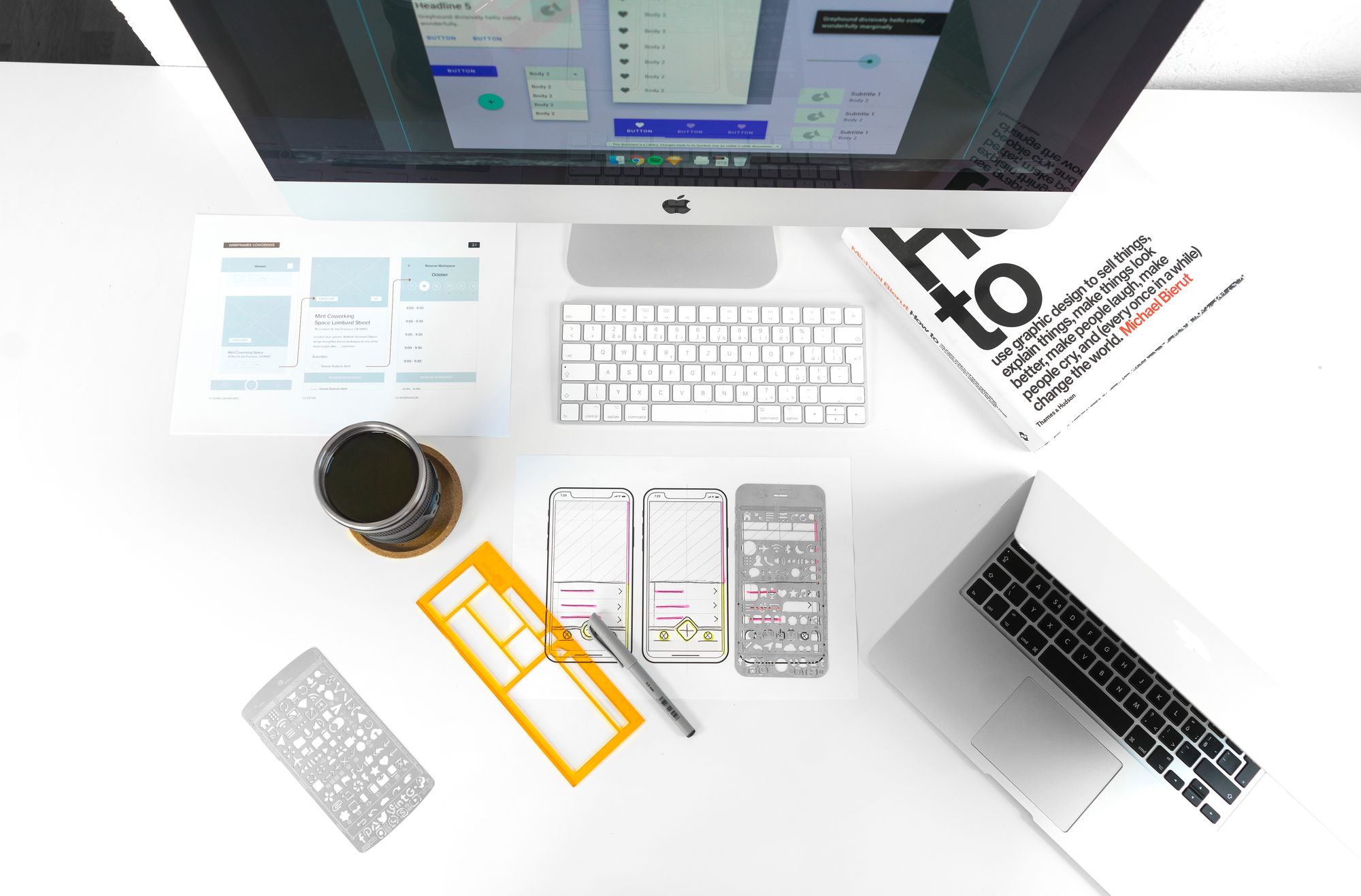 White desk with laptop, wireframe stensils and coffee and other UX tools