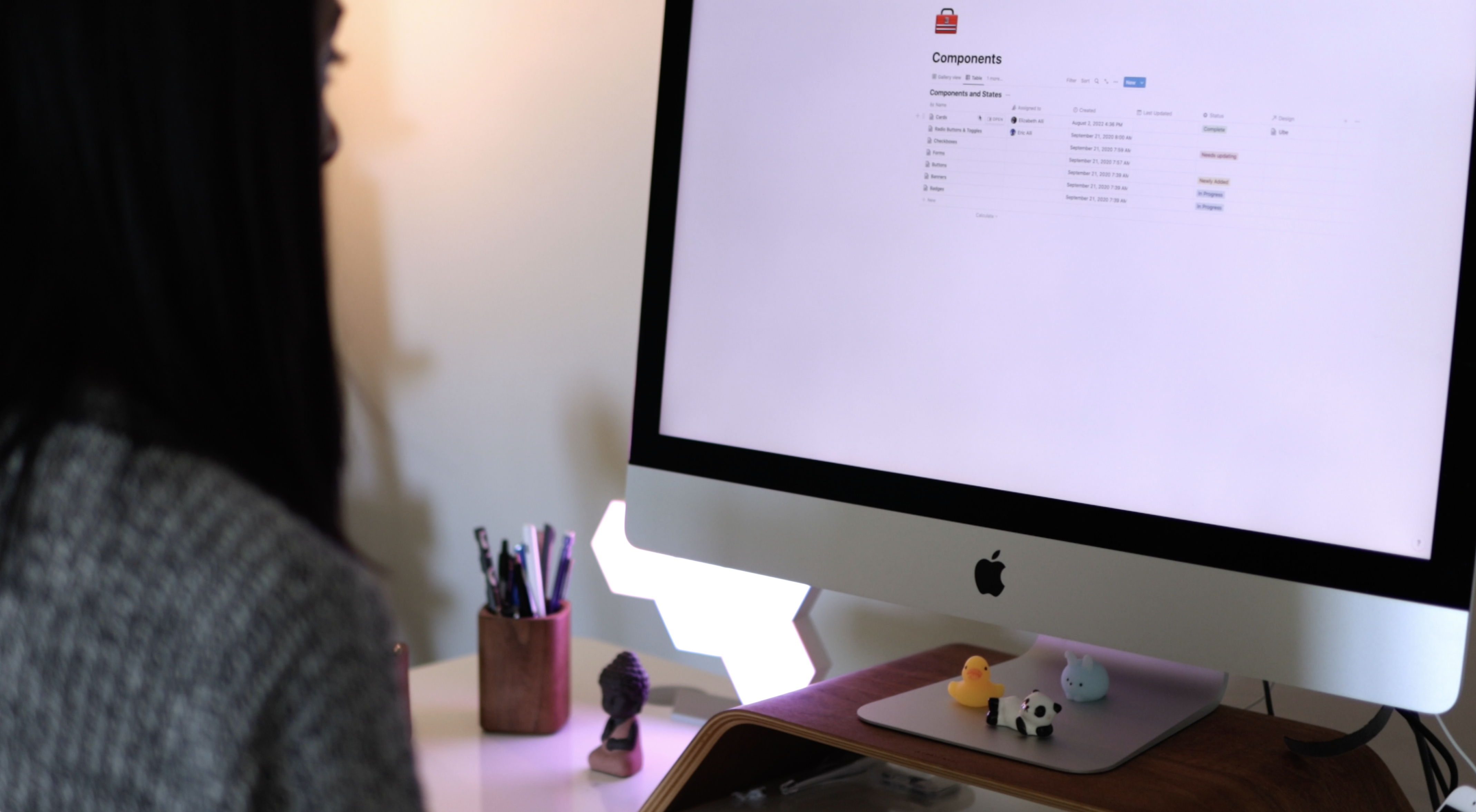 Woman sitting at desk looking at design system with little miniture animal figurines on desk