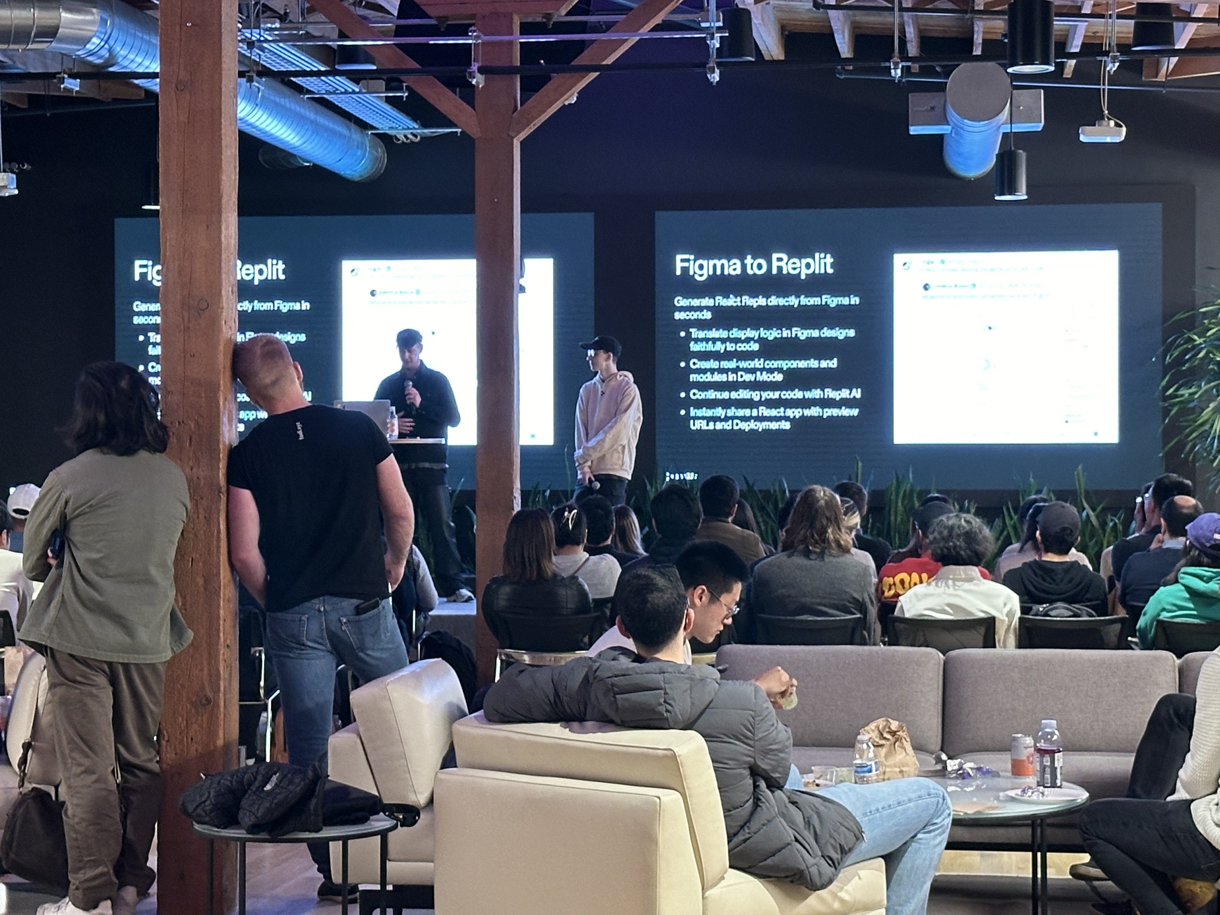 People standing and sitting watching a presentation on two large projectors